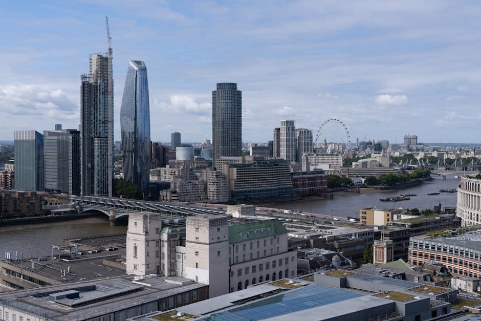 The image depicts an urban riverside scene with a concrete bridge spanning across the water, featuring visible support pillars and a roadway on top. In the background, tall modern buildings are visibl
